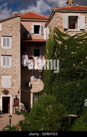 Edifici tradizionali in pietra con lavanderia e vigne verdi - Budva, Montenegro Foto Stock