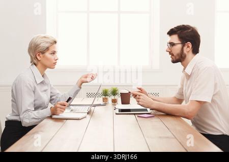 Discussione di lavoro tra due professionisti in un tavolo con notebook e impianti Foto Stock