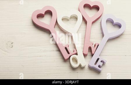 Tasti colorati a forma di cuore disposti in un display creativo su una superficie di legno Foto Stock
