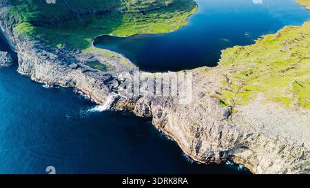 Vista aerea mozzafiato della costa frastagliata e del lussureggiante paesaggio delle Isole Faroe Foto Stock
