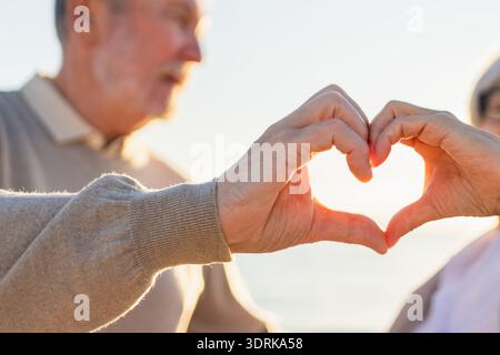 L'amore il cuore forma la pace. Coppia anziana che fa forma al cuore con le mani. Adulto maturo vecchio marito moglie mostra cuore sig Foto Stock