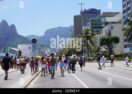 Le persone sono viste camminare, andare in bicicletta e pattinare su Ave. Vieira Souto, sulla spiaggia di Ipanema. Dietro, l'iconico "due fratelli" (Dois Irmão). Foto Stock