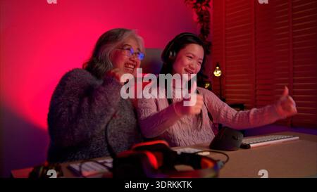 Nonna felice che gioca con il nipote in una stanza illuminata al neon Foto Stock