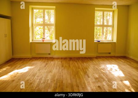 Camera vuota in un vecchio edificio di appartamenti con pavimento in parquet e finestre in legno Foto Stock