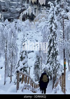Un escursionista attraversa un ponte ghiacciato sul sentiero escursionistico del Korouoma Canyon, Lapponia, Finlandia Foto Stock