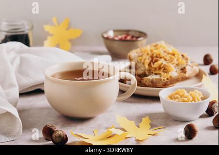 Tè autunnale in una tazza con crostini di mele su un piatto sul tavolo Foto Stock