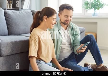 Giovane coppia che usa lo smartphone, trascorrendo del tempo su Internet nel weekend a casa Foto Stock