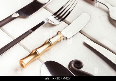 Collezione di argenteria disposta su un tavolo con un focus su un coltello d'oro unico Foto Stock