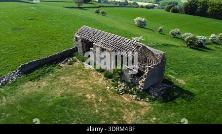 Vista aerea di un fienile di un contadino in pietra abbandonato in un lussureggiante paesaggio rurale Foto Stock