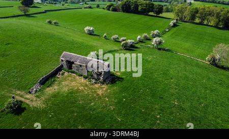 Vista aerea di un fienile di un contadino in pietra abbandonato in un lussureggiante paesaggio rurale Foto Stock