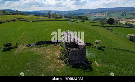 Vista aerea di un fienile di un contadino in pietra abbandonato in un lussureggiante paesaggio rurale Foto Stock