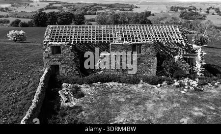 Vista aerea di un fienile di un contadino in pietra abbandonato in un paesaggio rurale bianco e nero Foto Stock
