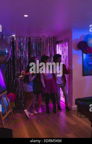 I ragazzi festeggiano a casa con palloncini e ballo da discoteca, divertendosi insieme. Festeggiamenti, adolescenti, danza, festa, amici Foto Stock