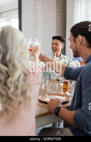 Gli amici brindano con un drink al ricevimento di nozze, festeggiando con gioia e risate. Festeggiamenti, amicizia, gioia, riunione Foto Stock
