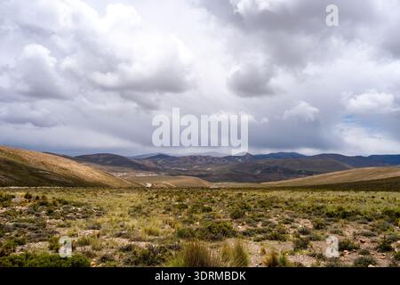 Una vasta e arida valle sotto un cielo spettacolare in Perù, che mostra la bellezza naturale del deserto e le montagne circostanti. Foto Stock