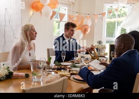 Sposi e sposi possono gustare un pasto nuziale con gli ospiti a un tavolo splendidamente decorato. festeggiamenti, felicità, cena, brindisi, feste Foto Stock