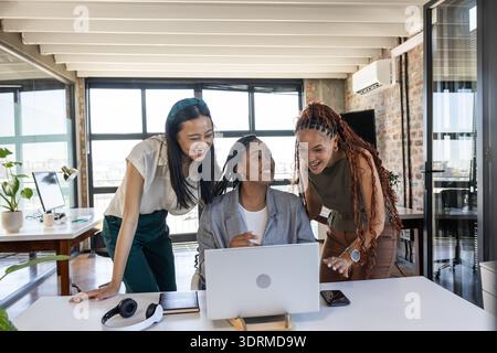 Colleghi che celebrano il successo del notebook in un ufficio moderno, condividendo momenti di gioia. Lavoro di squadra, collaborazione, business, raggiungere Foto Stock