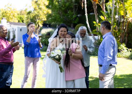 In giardino, la sposa abbraccia la donna come ospiti applaudendo e festeggiando con gioia. matrimoni, festeggiamenti, abbraccio, anche all'aperto Foto Stock