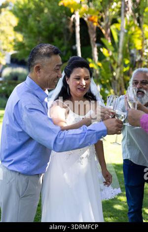 Sposa e ospiti brindano con bicchieri di champagne durante la celebrazione di nozze senior all'aperto. festa, festa, felicità, saluti Foto Stock