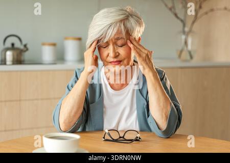 Mal di testa, infelice donna anziana di mezza età che soffre di mal di testa malata che sfrega i templi a casa. Vecchio nonno anziano maturo Foto Stock
