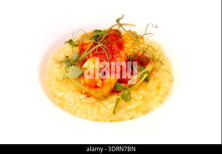 Risotto gourmet con riso cremoso condito con vivace salsa di pomodoro, succulenti gamberi e microgreen freschi, bellissimo Foto Stock
