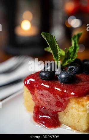 Primo piano della torta di semola con salsa di fragole e mirtilli. Foto Stock