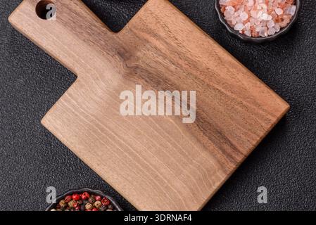Legno, un tagliere di legno vuoto su un tavolo da cucina scuro. Tagliere in legno Foto Stock