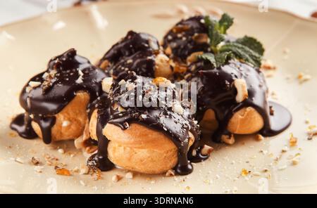 Delizioso dessert servito in un piatto con cioccolato e noci a un tavolo da pranzo Foto Stock