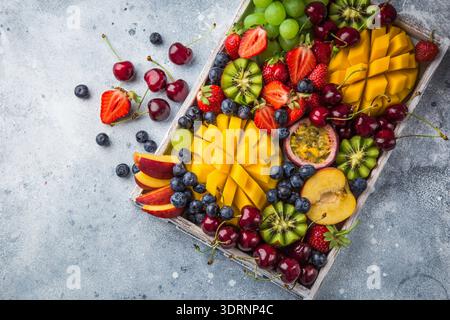 Vassoio di frutta e frutti di bosco deliziosi. Mango, kiwi, fragola, uva, ciliegia, mirtillo, pesca e frutto della passione Foto Stock
