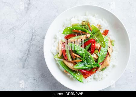 Mescolare il pollo e le verdure con il riso in un recipiente bianco Foto Stock