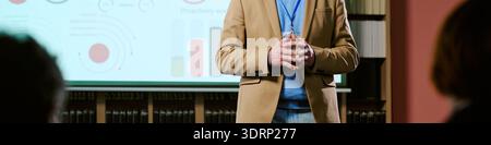 Presentazione dell'uomo caucasico di mezza età davanti ai grafici proiettati Foto Stock