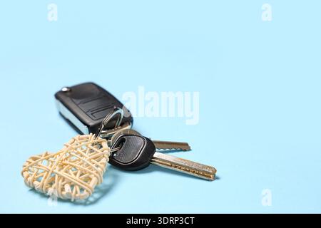 Chiavi per auto con portachiavi a forma di cuore su sfondo blu, primo piano Foto Stock