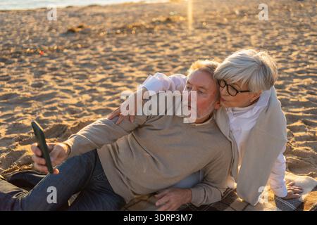 Videochiamata. Coppia senior che fa selfie con videochiamata in spiaggia all'aperto. Il nonno della vecchia nonna matura parla Foto Stock