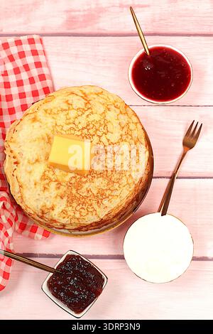 Deliziosi pancake russi con marmellata, formaggio fresco, conserve, panna acida e miele su un tavolo di marmo. Colazione salutare Foto Stock