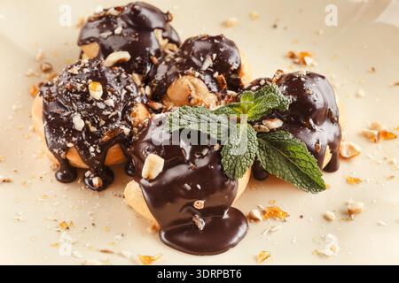 Delizioso dessert con salsa al cioccolato e menta su un piatto ripieno di noci e biscotti tritati Foto Stock