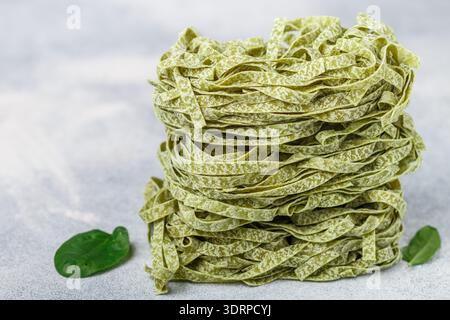 Materie casalingo italiano pasta verde tagliatelle con spinaci close-up. Asciugare gli spaghetti. Messa a fuoco selettiva, spazio di copia Foto Stock