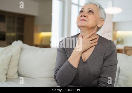 Triste stanca malata malata solitaria delusa anziana donna seduta a casa da sola. Infelice nonna matura che soffre di dolore Foto Stock