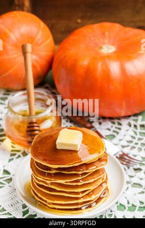 In casa la zucca frittelle con burro e miele su una piastra bianca sul tavolo. Utile e gustosa prima colazione. Messa a fuoco selettiva Foto Stock
