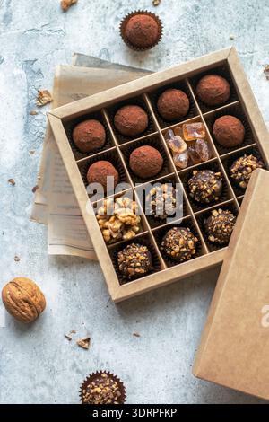 Set di tartufi di cioccolato con noci e cacao. Gustose caramelle rotonde. Un delizioso regalo in una scatola di carta Kraft. Concetto di vacanza. Selezionare Foto Stock