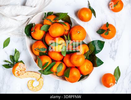 Agrumi biologici freschi mandarini arance (mandarini, clementine) con foglie in un piatto leggero su sfondo di marmo. Selezionare Foto Stock