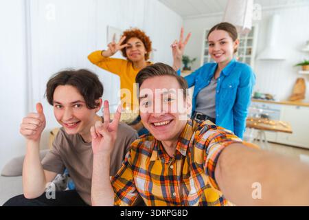 Salute Funky Mood. Amici felici fanno selfie. Uomo che fa una foto di amici alla festa. Gruppo di persone multirazziali che scattano foto Foto Stock