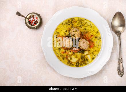 Deliziosa zuppa con polpette di pollo o tacchino con verdure - patate, carote, aneto, prezzemolo e spezie in un piatto bianco. Foto Stock