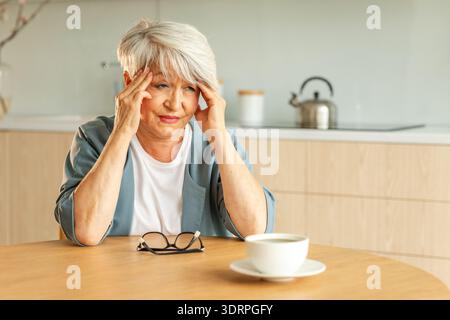 Mal di testa, infelice donna anziana di mezza età che soffre di mal di testa malata che sfrega i templi a casa. Vecchio nonno anziano maturo Foto Stock