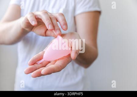 Donna che tiene la tazza mestruale rosa isolata su sfondo bianco. Donna moderna alternativa ecoginecologica igiene in menstr Foto Stock