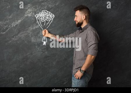 L'uomo tiene un disegno di fiori su una parete in uno studio durante il giorno Foto Stock