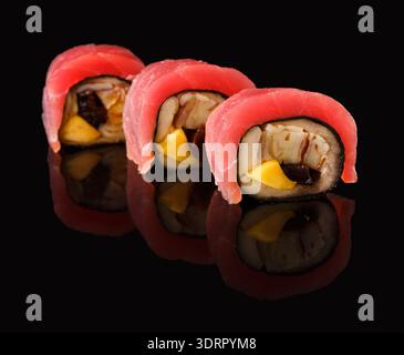 Collezione di sushi Rolls disposti su una superficie nera che riflette colore e forma Foto Stock