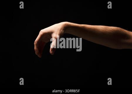 La mano che raggiunge un'ambientazione buia crea un collage di forme e gesti umani Foto Stock