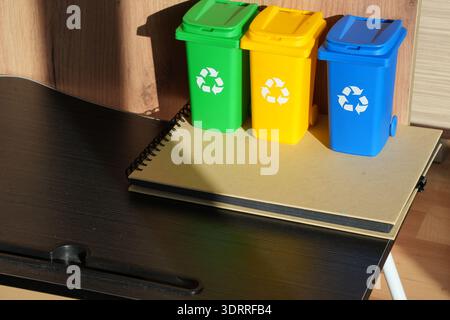 Contenitori di riciclo colorati sulla scrivania che simboleggiano lo stile di vita a rifiuti zero uffici sostenibili consapevolezza del clima responsabilità aziendale ESG e ambiente moderno Foto Stock