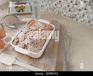 Pan di Spagna con petali, fiocchi di mandorle e zucchero a velo. Dessert e festa a casa. Cucina e hobby. Foto Stock