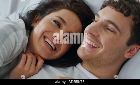 Primo piano felice coppia caucasica fidanzata fidanzata parlare sul letto casa camera da letto affronta donna uomo chiacchierare gossip ridere sorridere coccolare donna maschio Foto Stock